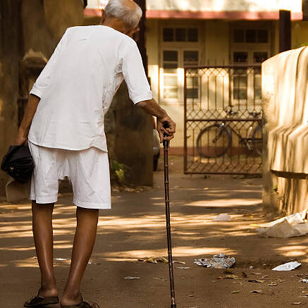 Mumbai, India - Nov 24, 2008.  An old indian man walks through the slums of Mumbai.